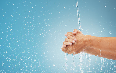 Image showing Water splash, cleaning hands and hygiene on blue background, advertising or product placement space. Health, skincare and safety from germs or bacteria, man washing hand in water in studio background