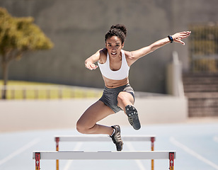 Image showing Jump, athlete and hurdle black woman in sports race, competition or training at stadium with energy, power and body challenge. Fast, speed and runner at an arena course or field for workout exercise