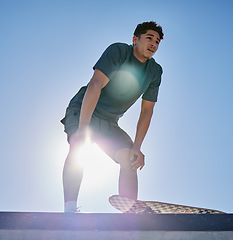 Image showing Young man, skateboard and freedom on blue sky lens flare at urban skate park, city and relaxing summer for training, outdoor action and sports hobby in USA. Skater ready for action jump risk off ramp