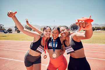 Image showing Medal, winner and athlete women at a stadium sports, competition or race success in group hug portrait. Runner people, team or friends with gold award, winning champion and achievement on race track