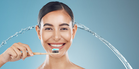 Image showing Woman brushing teeth, water splash and wellness, dental cleaning and mouth cosmetics on blue background in shower. Happy young model face portrait, toothpaste on toothbrush and healthy teeth smile