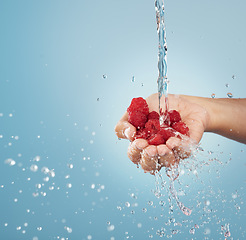 Image showing Hands with raspberry, water splash and studio mockup on blue background of summer fruit sustainability, healthy lifestyle and detox, nutrition and vitamin c. Clean, vegan and diet red berries in palm