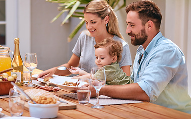 Image showing Family, food and lunch outdoor with child, mom and dad together for meal, wine and bonding at patio dining table. Baby, man and woman happy while eating outdoor in summer for healthy lifestyle