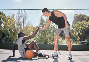 Image showing Sports, teamwork and men with helping hand in basketball, player giving support, help and assistance. Fitness, friends and man lifting black man with injury from ground on outdoor basketball court