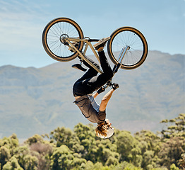 Image showing Mountain bike, man and upside down air jump, action and bicycle stunt, challenge and adventure, freedom or dynamic risk in sky. Biker athlete, sports adrenaline and energy in outdoor competition show