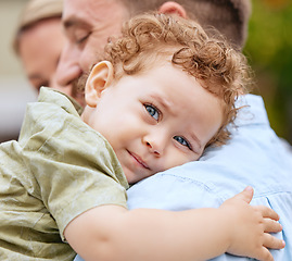 Image showing Baby, love and family with a boy hugging his father while spending time with his mother outdoor together. Kids, bonding and care with a male toddler embracing a parent while outdoor at the park