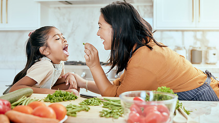 Image showing Health, eating and food with mother cooking in kitchen with nutrition, vegetables and care. Home, lunch and healthy diet of asian family with young daughter tasting green veggies with mom.