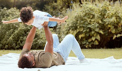 Image showing Father, kid and fun time of a family in a nature park on a picnic blanket with parent love. Child, dad and in the air outside playing of a kid with a man on a summer day with young and care