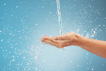 Image showing Woman, hands and water splash on blue background in studio for healthcare, cleaning and washing hands. Zoom, model and pouring fresh faucet liquid in earth sustainability, conservation and protection