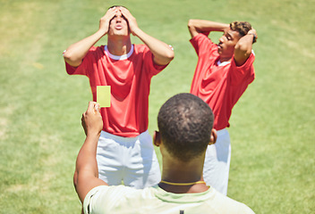 Image showing Sports, soccer and referee with yellow card standing on field with upset, angry and mad soccer players. Foul, mistake and athlete getting warning for rules violation in game or match on soccer field