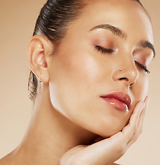 Image showing Makeup, beauty and face of a woman with a glow from cosmetics against a brown studio background. Skin, care and young cosmetic model touching facial art with natural glam for facial elegance