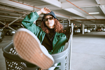 Image showing City, parking lot and woman sitting in shopping cart with urban fashion and cars parking in background. Cool hip hop street style, fun girl from Brazil with freedom and youth on weekend in Sao Paulo.