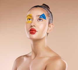 Image showing Makeup, clown and young woman with facial art, natural beauty and wellness with brown studio background. Artist, female and girl being creative, with pride and confident with cosmetics or face paint.