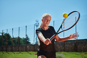 Image showing A young girl showing professional tennis skills in a competitive match on a sunny day, surrounded by the modern aesthetics of a tennis court.