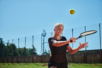 Image showing A young girl showing professional tennis skills in a competitive match on a sunny day, surrounded by the modern aesthetics of a tennis court.