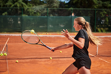Image showing A young girl showing professional tennis skills in a competitive match on a sunny day, surrounded by the modern aesthetics of a tennis court.