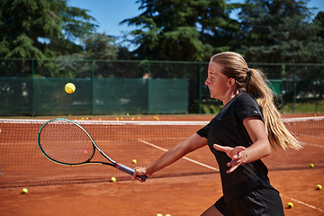 Image showing A young girl showing professional tennis skills in a competitive match on a sunny day, surrounded by the modern aesthetics of a tennis court.