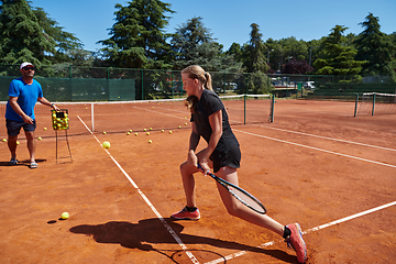 Image showing A professional tennis player and her coach training on a sunny day at the tennis court. Training and preparation of a professional tennis player