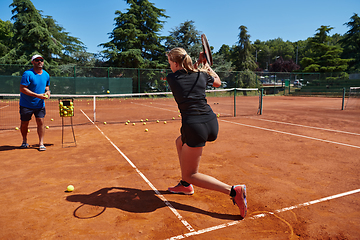 Image showing A professional tennis player and her coach training on a sunny day at the tennis court. Training and preparation of a professional tennis player