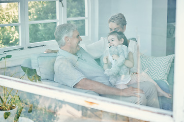 Image showing Family, girl with teddy bear and grandmother and grandfather in home, having fun and bonding. Support, care and love of happy grandparents playing with kid holding toy on sofa in house living room.