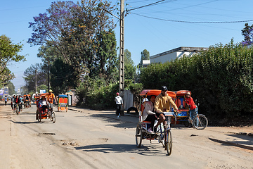 Image showing Traditional rickshaw bicycle with Malagasy people on the street of Antsirabe, one of the ways to earn money. Everyday life on the street of Madagascar.