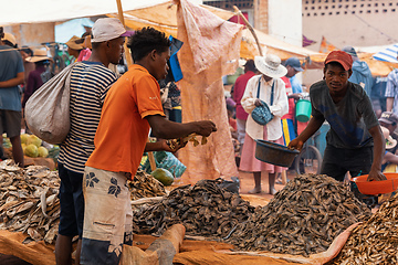 Image showing Malagasy man buys dried fish at a street market. Fishing is one of the livelihoods in Madagascar.