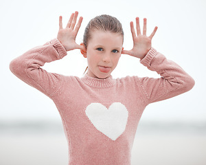 Image showing Girl, funny face and tongue for comic emoji with child on vacation, adventure or travel with freedom, fun and happiness outdoor. Portrait of young kid model playing on holiday in Ireland nature