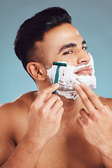 Image showing Beauty, skincare and man shaving beard for clean face for dermatology, health and wellness on blue studio background. India male model with foam for healthy skin after facial shave and self care