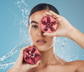 Image showing Pomegranate, skincare and beauty woman with water splash in studio blue mock up for healthy, wellness and skin glow advertising. Young woman with vitamin c fruits for facial product marketing mockup