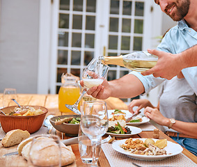 Image showing Family, celebration and hand pouring wine in glass at lunch, having fun and drinking together. Holiday, festival and couple eating food, drink champagne and celebrating at dinner table in family home