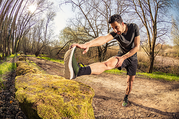 Image showing Male runner stretching outdoors