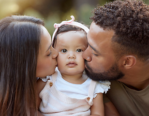 Image showing Mother, father and baby face kiss while bonding in a garden outdoors with love, care and affection. Loving, caring parents kissing little daughter while bond in nature for calm relaxation