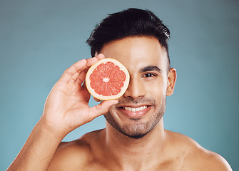 Image showing Grapefruit, man and skincare in studio for vitamin c, healthy wellness and natural glow on blue background. Portrait of happy guy model face, nutrition and body detox for cleaning beauty cosmetics