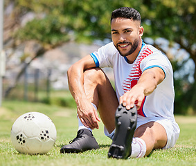 Image showing Soccer ball, field and man stretching legs on grass for sport training or exercise workout. Portrait of young happy athlete, healthy lifestyle motivation and cardio warm up for football competition