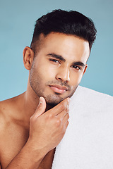 Image showing Hand, face and beauty with a man model posing in studio on a blue background for grooming or skincare. Portrait, luxury and wellness with a male indoors to promote a natural product or skin treatment