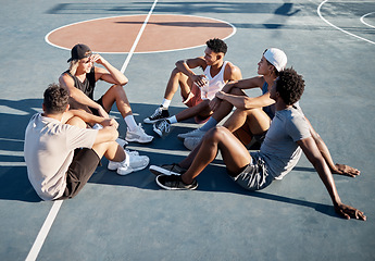 Image showing Fitness, friends and relax on basketball court floor with basketball players group bond, resting and talking on a break. Sports, resting and men sitting on the ground at outdoor court after training