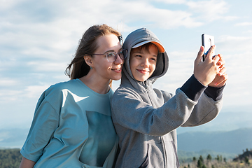 Image showing A child takes a selfie on a smartphone with mom