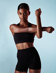 Image showing Woman, fitness or stretching arms on blue background in workout studio, training or exercise. Portrait, model or sports athlete in warmup for health wellness, body performance or muscle power