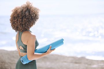 Image showing Black woman, yoga mat and enjoying ocean and view before zen, peaceful and relaxing exercise. A yogi and woman ready to meditate at beach. Nature, african american girl and meditation by sea