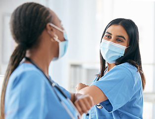 Image showing Health, covid and mask, women in hospital greeting and safety for healthcare in pandemic and touch elbow for hello or celebrate. Doctor, team and medical professional with protection in clinic.