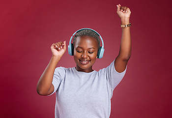 Image showing Music, dance and freedom with a black woman in studio on a red background for dancing or fun. Dancer, headphones and carefree with a young female streaming audio with an online service for enjoyment