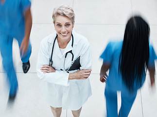 Image showing Portrait, happy and doctor in busy hospital standing with crossed arms after consultation. Happiness, medicine and senior healthcare professional with stethoscope working in medical clinic in Canada.