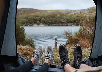 Image showing Shoes, camping and tent with a couple by a lake out in nature while hiking for adventure or travel together. Water, forest and freedom with a man and woman outdoor in the mountain to relax or getaway