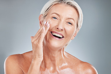 Image showing Senior woman, beauty and smile for skincare, moisturizer or cosmetic treatment against a grey studio background. Happy elderly female smiling with teeth in satisfaction for perfect facial skin cream
