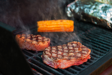 Image showing Beef steaks on the grill with flames