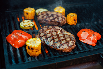 Image showing Beef steaks on the grill with flames