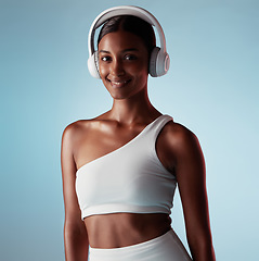 Image showing Radio, smile and woman with headphones for music, podcast or motivation during exercise against a blue mockup studio background. Audio, happy and Indian girl training for fitness, energy and cardio