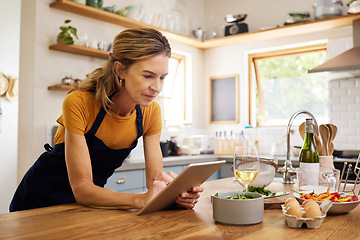 Image showing Woman, tablet and kitchen for online recipe, browsing or research in cooking or baking at home. Female with apron checking instructions on the internet for meal or ingredients on touchscreen indoors