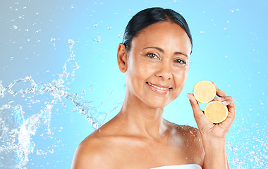 Image showing Lemon, skincare and beauty woman in studio mock up water splash for face, facial wellness and healthy glow portrait for advertising. Model with fruit for dermatology or vitamin c on blue mockup