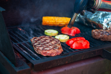 Image showing Beef steaks on the grill with flames
